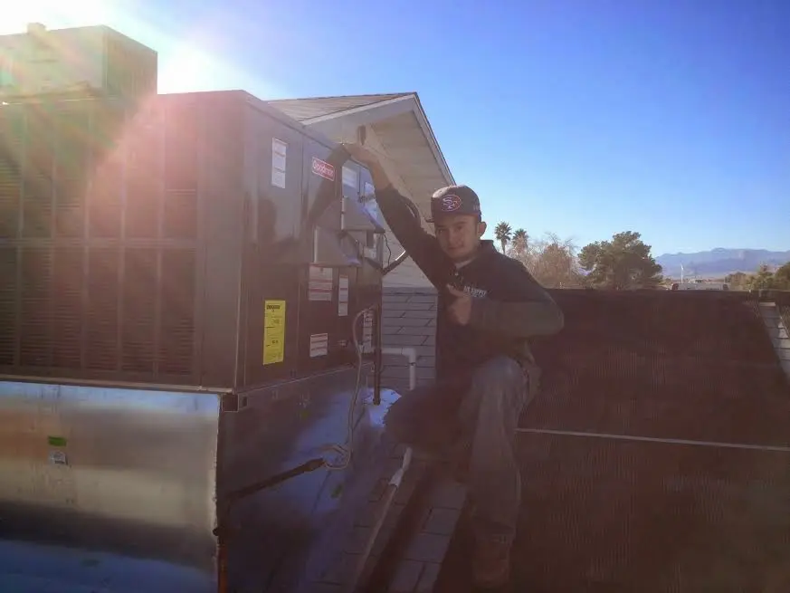 HVAC technician performing Heat Pump Repair on a rooftop unit in Cushing